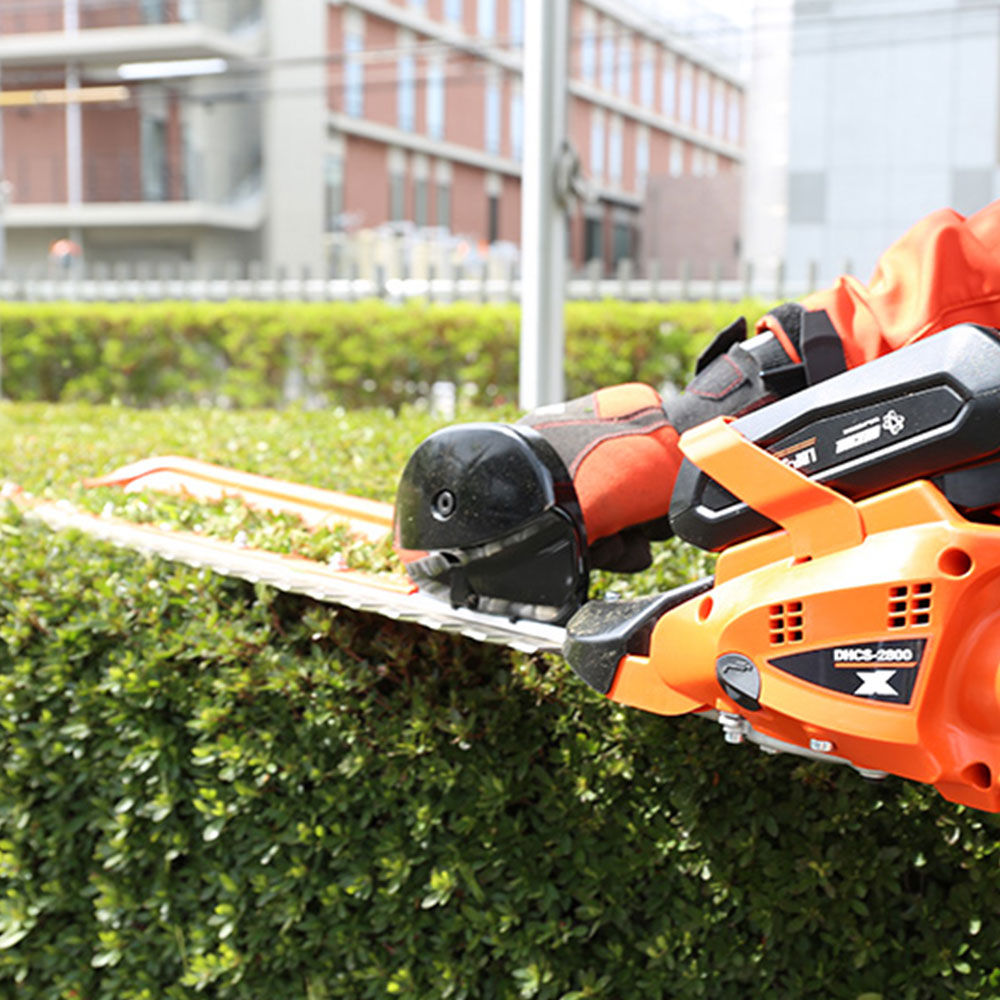0tl40zhc2m1.jpg - Mowers Online Electric hedge trimmer with safety helmet on shrub