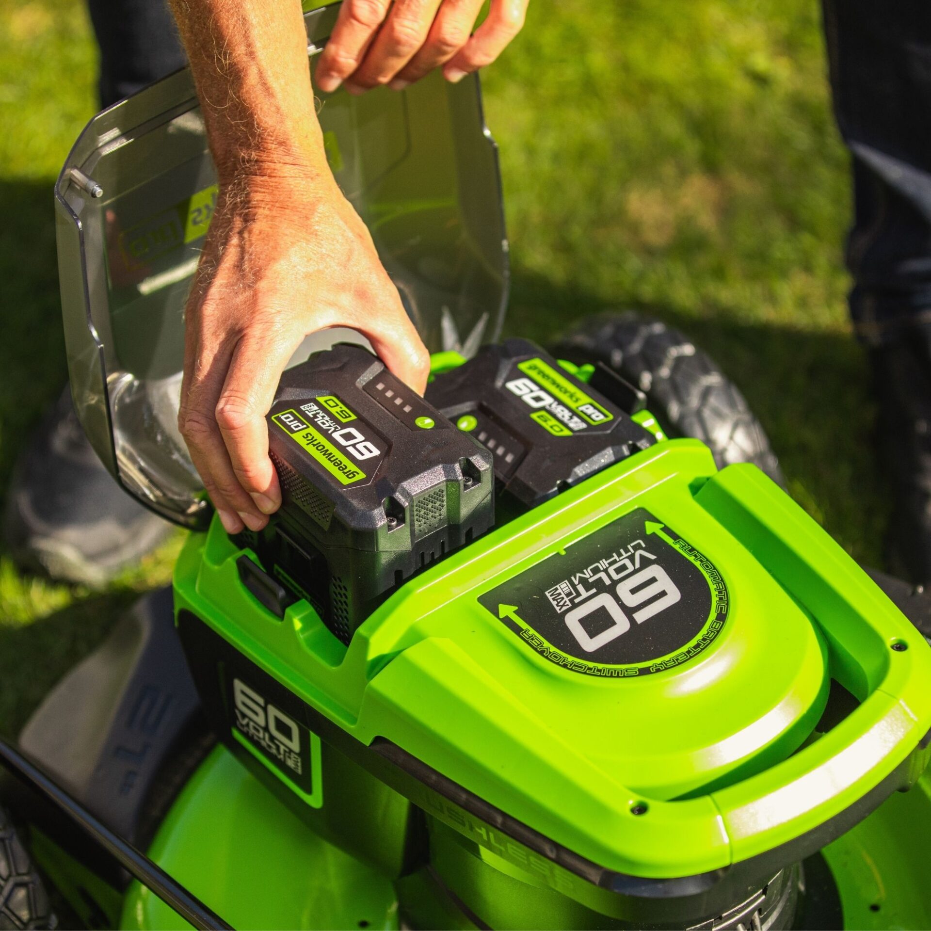 wvjgmgwfum0.jpg - Mowers Online Person holding green cordless lawn mower with batteries