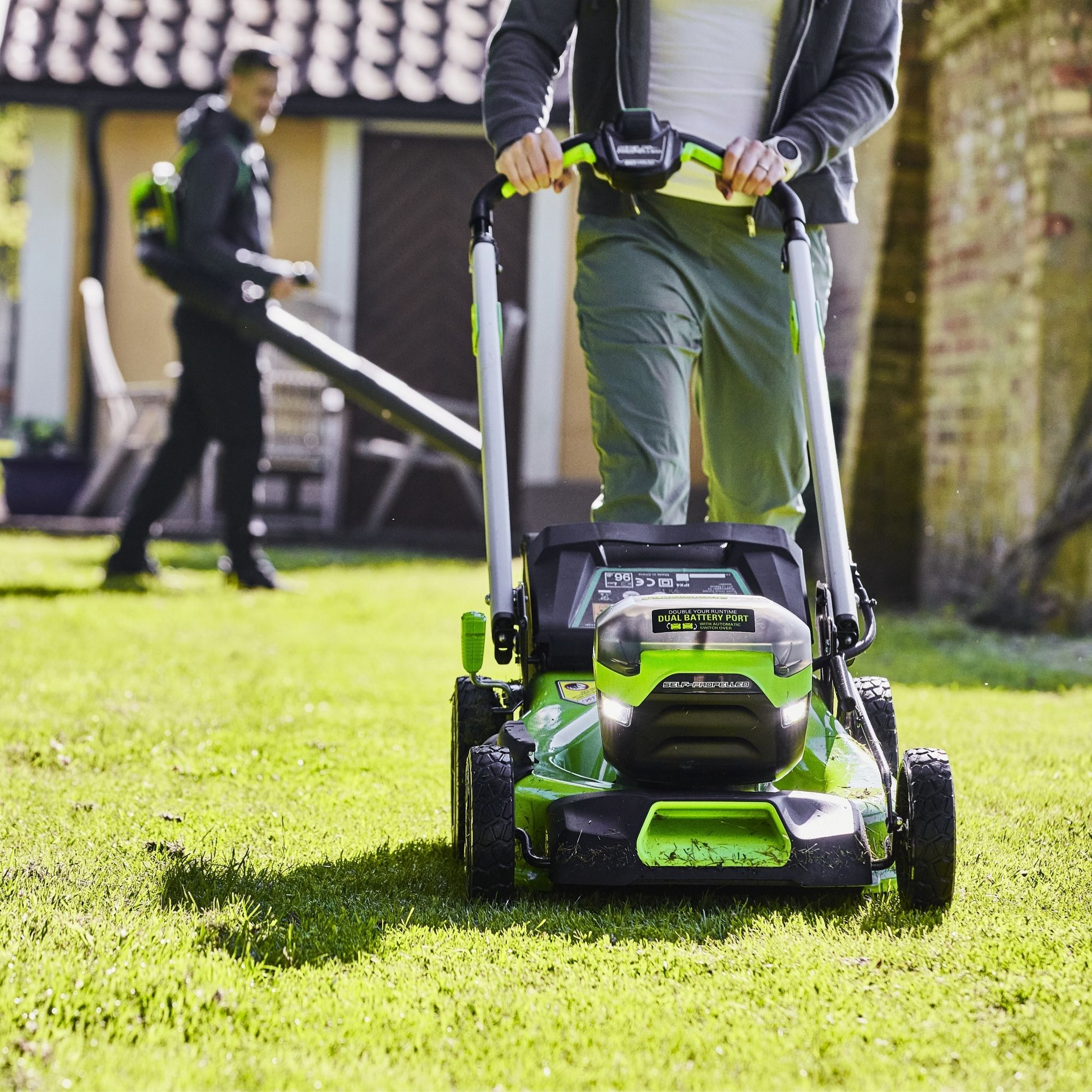 ylm3i3h4nbm.jpg - Mowers Online Person using green cordless lawn mower on grass